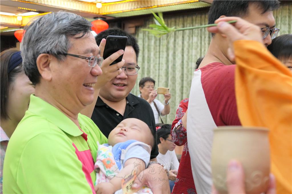佛光會壽山分會會長李旺政抱著7個月大的金孫蒙受灑淨.jpg