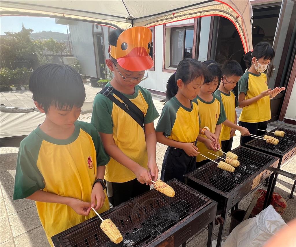 大小童軍一起字排開專注翻轉烤玉米。.jpg