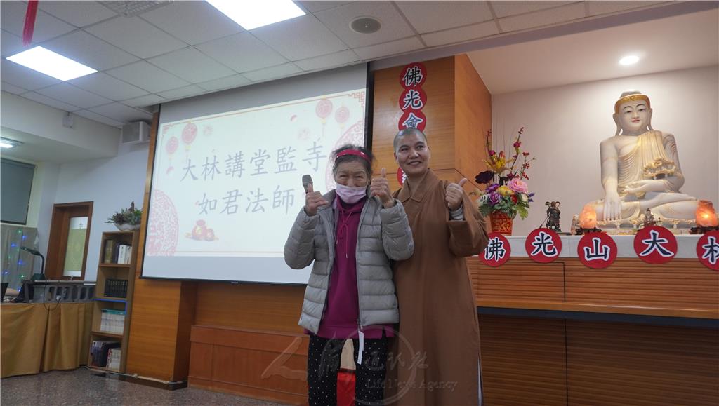 如君法師特別表揚風雨無阻、全年無休，每天一大早就來道場清潔環境的老菩薩江月秀，為他穿上羽絨外套。.jpg