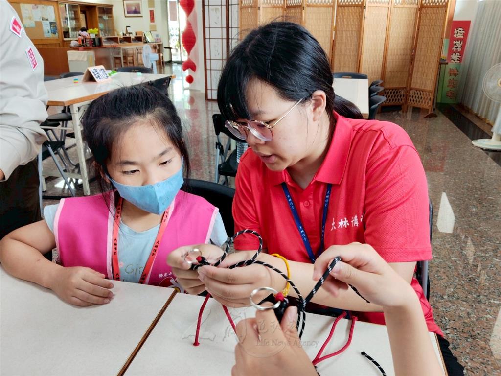 小隊輔協助指導編織繩結鑰匙圈，小朋友專注學習。.png