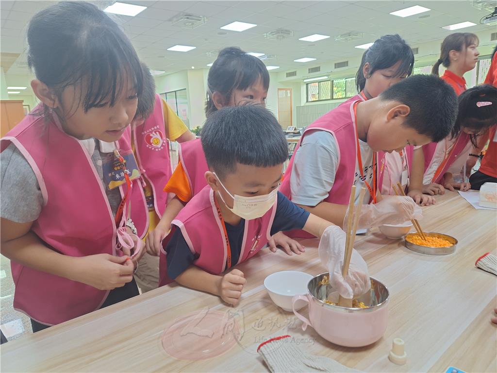 大地闖關遊戲「長者體驗」。孩子們藉由戴手套使用筷子夾小餅乾的體驗，從中體會長者手部不靈活造成生活的不